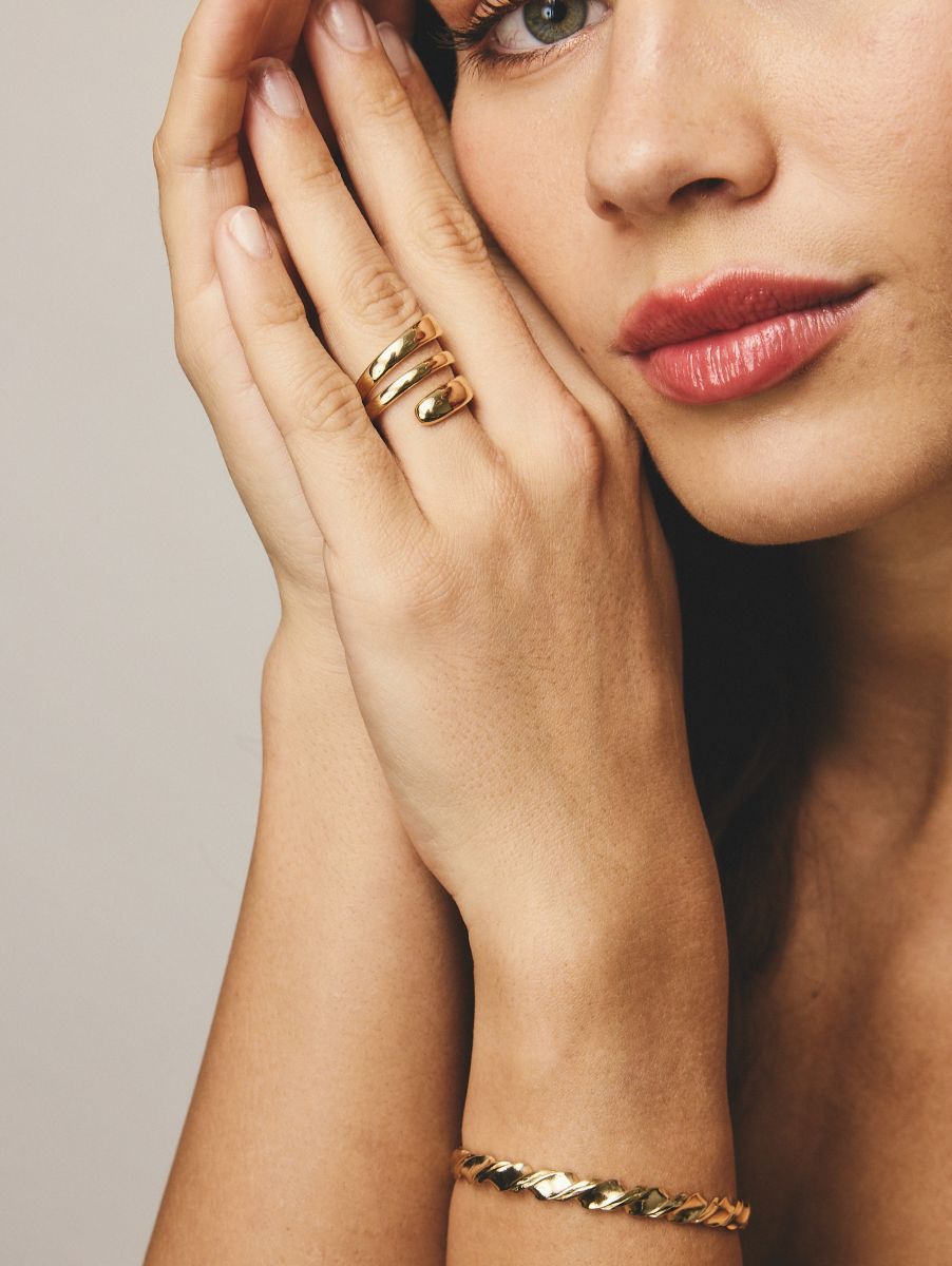 Stacked gold rings worn on a model's hand